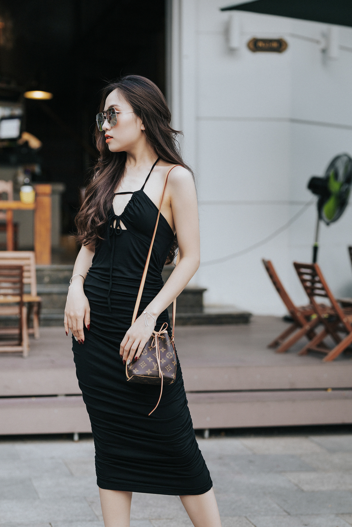 Fashionable Asian model in black dress with accessories on street