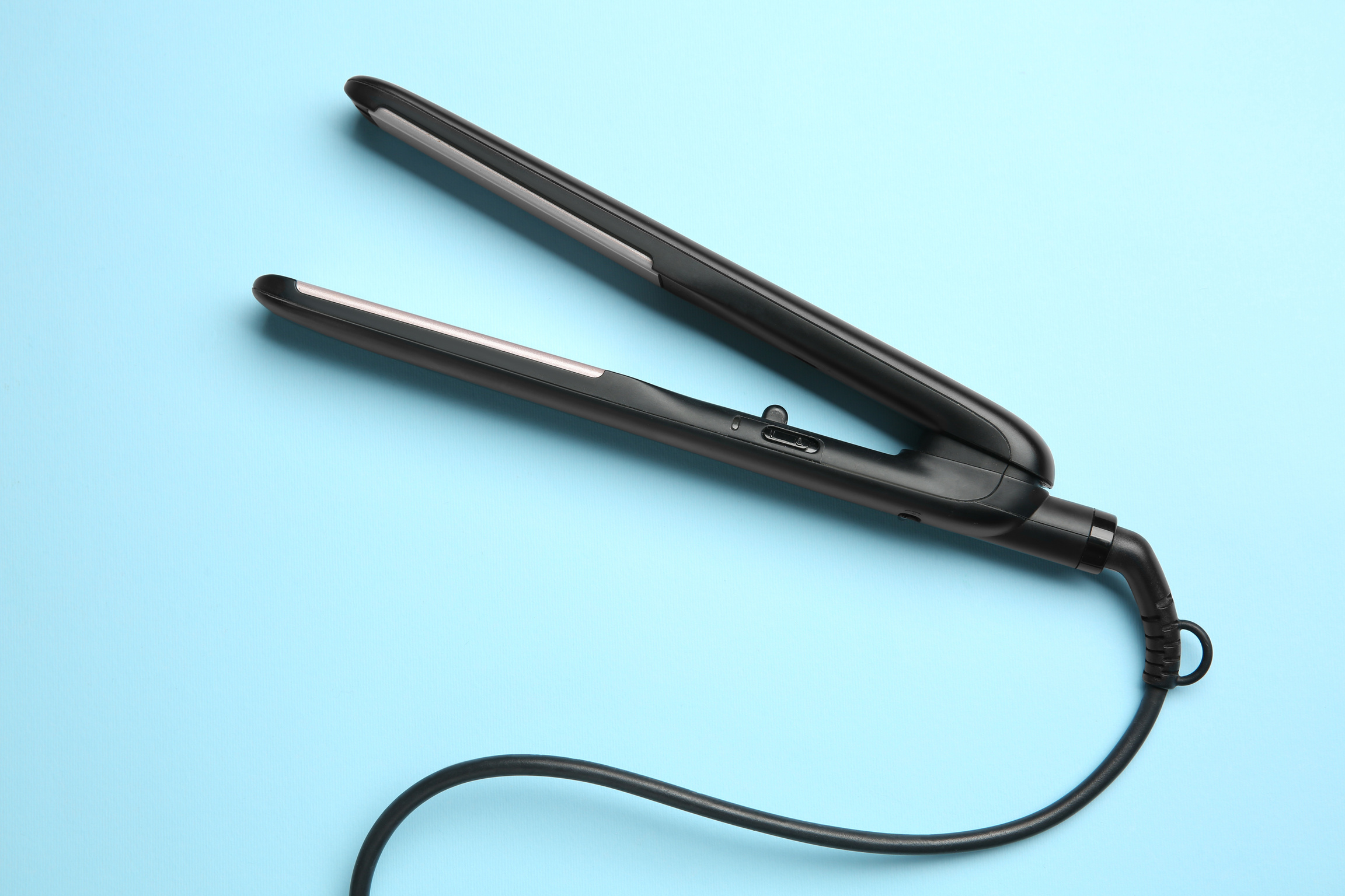 Modern Flat Hair Iron on Light Blue Background, Top View